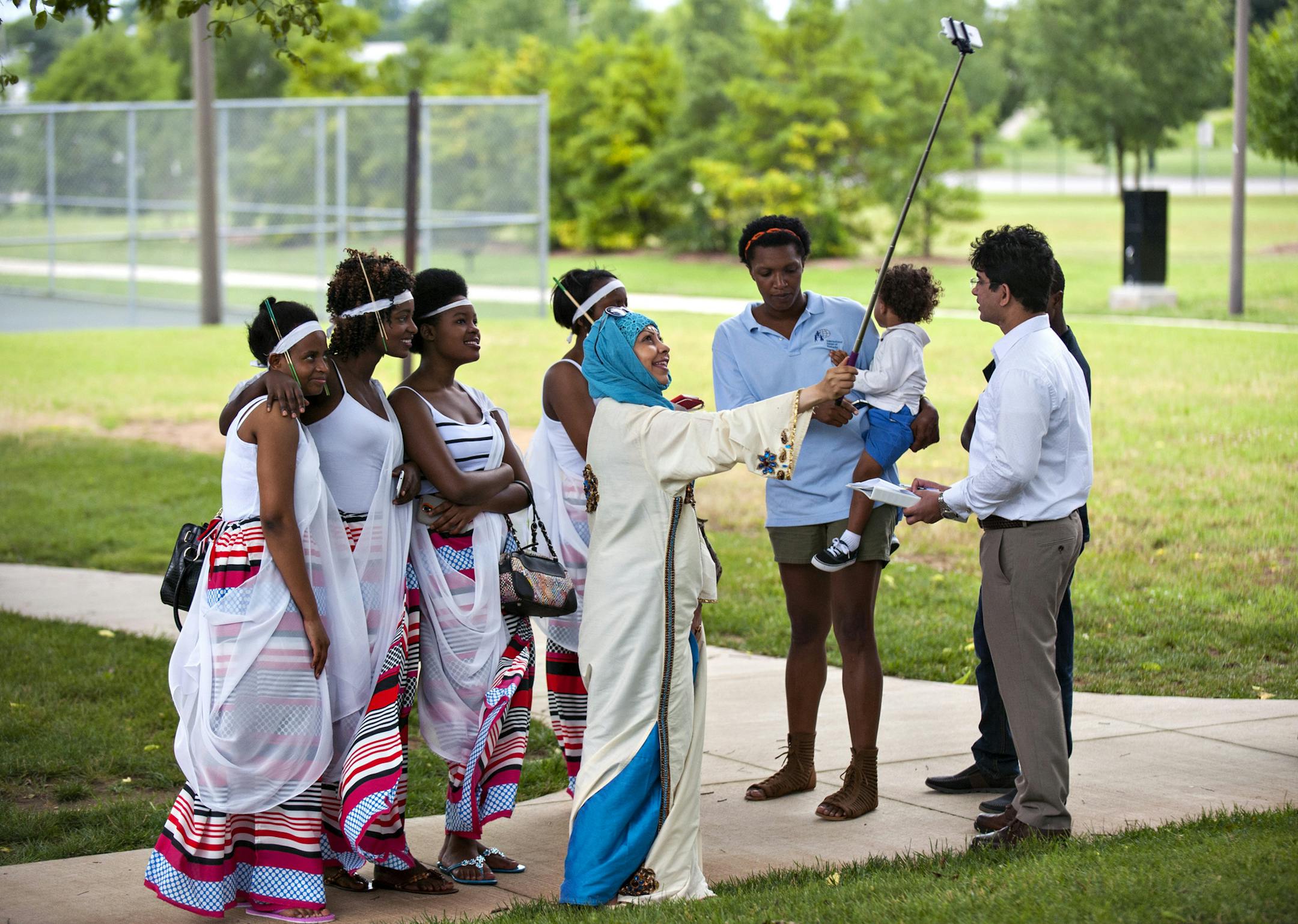 Sukainah Alshahab wears traditional dress from Saudia Arabia as she takes a selfie with women from Rwanda at International Center of Kentucky's World Refugee Day Fest at Roland Bland Park in Bowling Green, Ky. on Saturday, June 20, 2015. (Miranda Pederson/Daily News via AP)