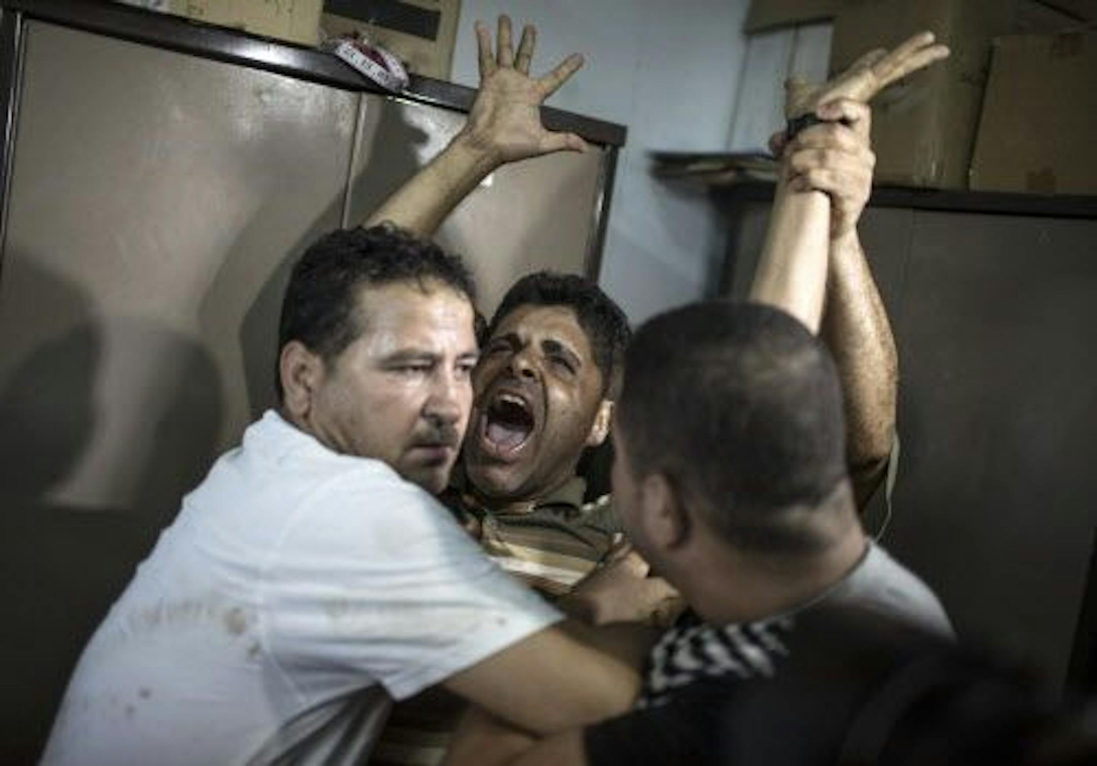 Men restrain Tarek al-Rifi, center, who reportedly lost a child in an Israeli airstrike, at the Al-Shifa Hospital in Gaza City, Aug. 21, 2014.