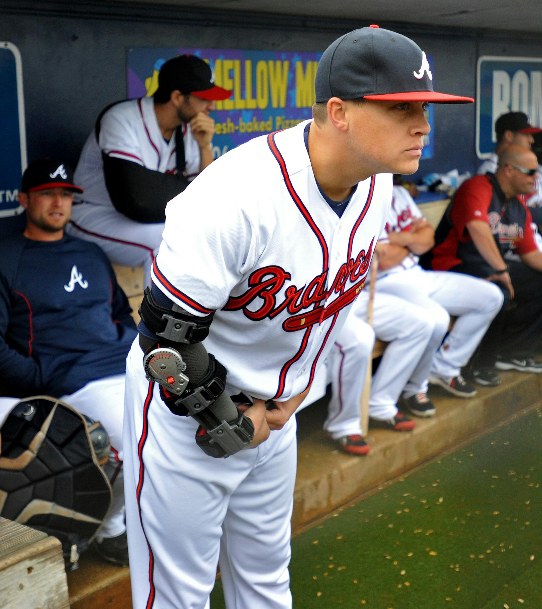 Atlanta Braves pitcher Kris Medlen wears an elbow brace on his right arm after season-ending Tommy John surgery as he waits during a rain delay in their exhibition baseball game against the team's minor league Future Stars Saturday, March 29, 2014, in Rome, Ga. (AP Photo/David Tulis) ORG XMIT: MIN2014041419571366