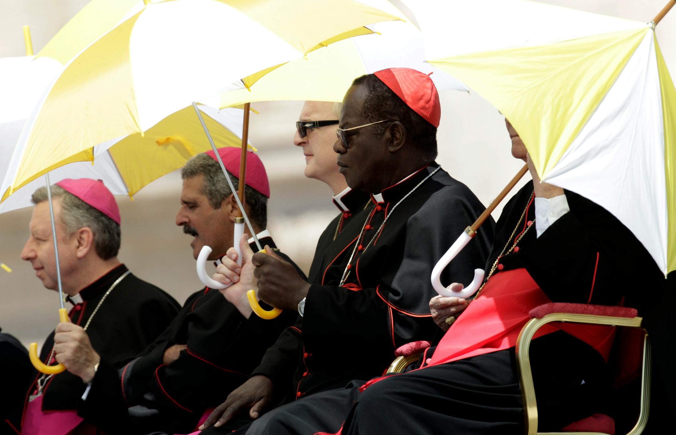 Bishops shelter themselves from the sun under umbrellas bearing the colors of the Vatican state during Pope Benedict XVI weekly general audience in St. Peter's Square at the Vatican, Wednesday, May 30, 2012. The Pontiff broke his silence over the scandal of leaked documents that has convulsed the Vatican, saying he was saddened by the betrayal but grateful to those aides who work faithfully and in silence to help him do his job. (AP Photo/Riccardo De Luca)