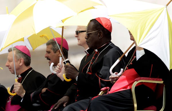 Bishops shelter themselves from the sun under umbrellas bearing the colors of the Vatican state during Pope Benedict XVI weekly general audience in St