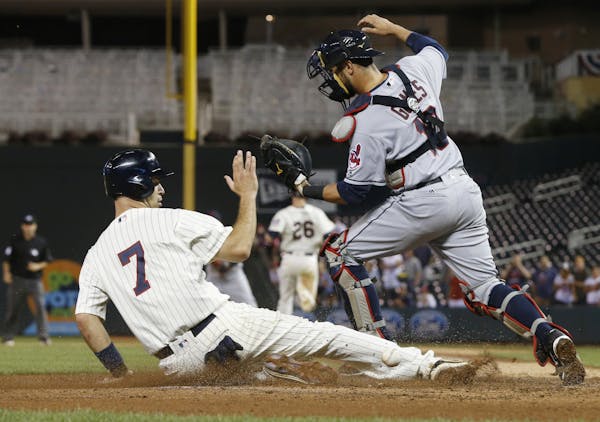 Minnesota Twins' Joe Mauer scores the go-ahead run as Cleveland Indians catcher Yan Gomes can't handle the throw to the plate on a fielder's choice wi