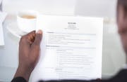 Close-up Of A Businessman Looking At Resume Holding In Hand