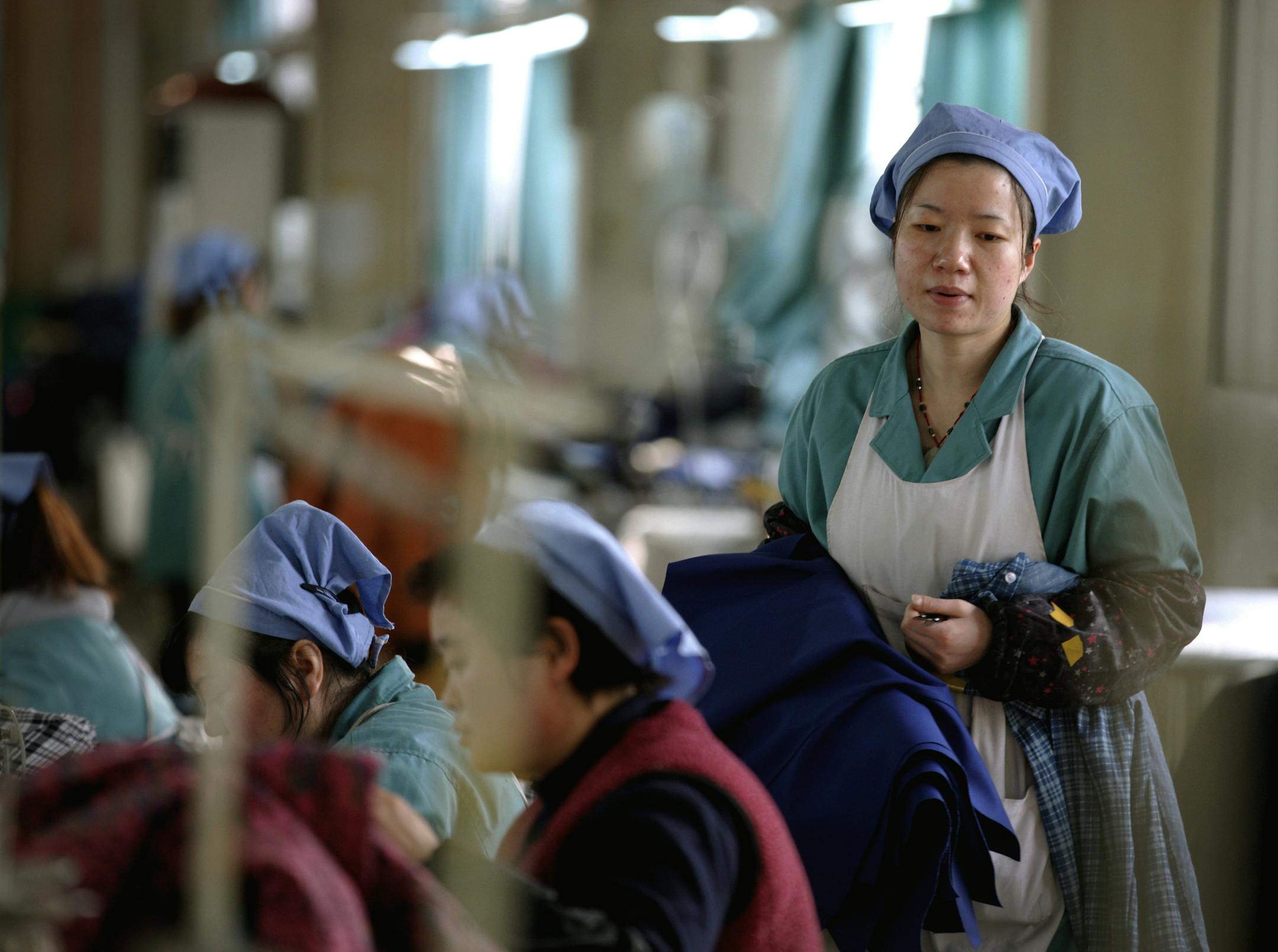 Women work at a garment factory in Huaibei in central China's Anhui province Tuesday, Jan. 20, 2015. China's economic growth slowed to 7.4 percent last year, the weakest expansion in more than two decades. The numbers released Tuesday, are still miles ahead of growth rates in major industrialized economies, but represent a sharp decline from double digit growth in previous years. That adds to pressure on the country's communist leaders as they try to prevent a sharper slowdown in 2015 while over