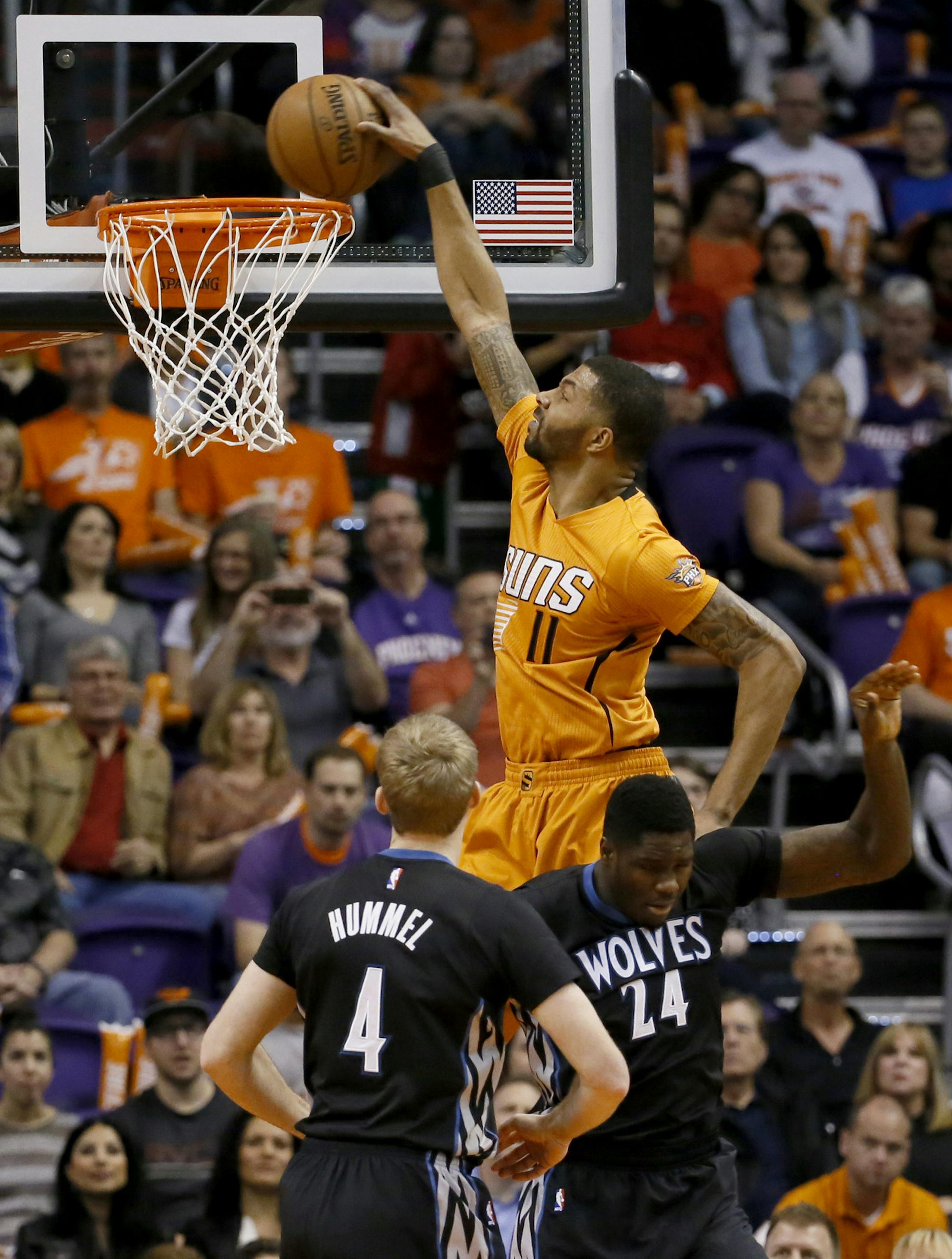 Phoenix Suns' Markieff Morris (11) dunks over Minnesota Timberwolves' Anthony Bennett (24) as Robbie Hummel (4) looks on during the first half of an NBA basketball game, Friday, Jan. 16, 2015, in Phoenix. (AP Photo/Matt York)