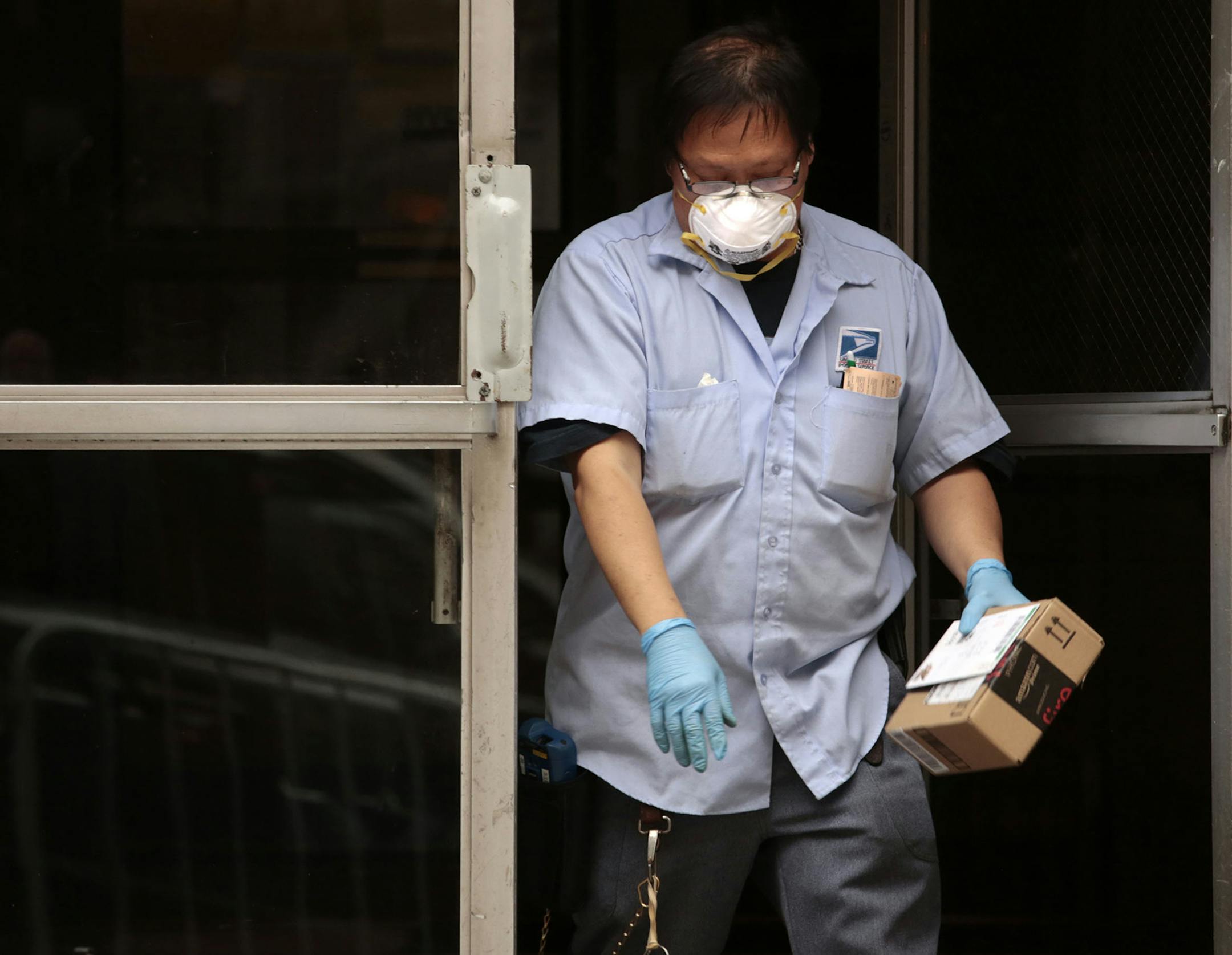 At the apartment of Dr. Craig Spencer, on W. 147th St. in Harlem, USPS carrier Keven Ngo (spelling is cq) wears a mask and gloves to deliver the mail on Friday, Oct. 24, 2014. He did not wear it on the rest of his route. Dr. Spencer is the first reported case of Ebola in New York. (Carolyn Cole/Los Angeles Times/MCT) ORG XMIT: 1159135 ORG XMIT: MIN1410241728344849