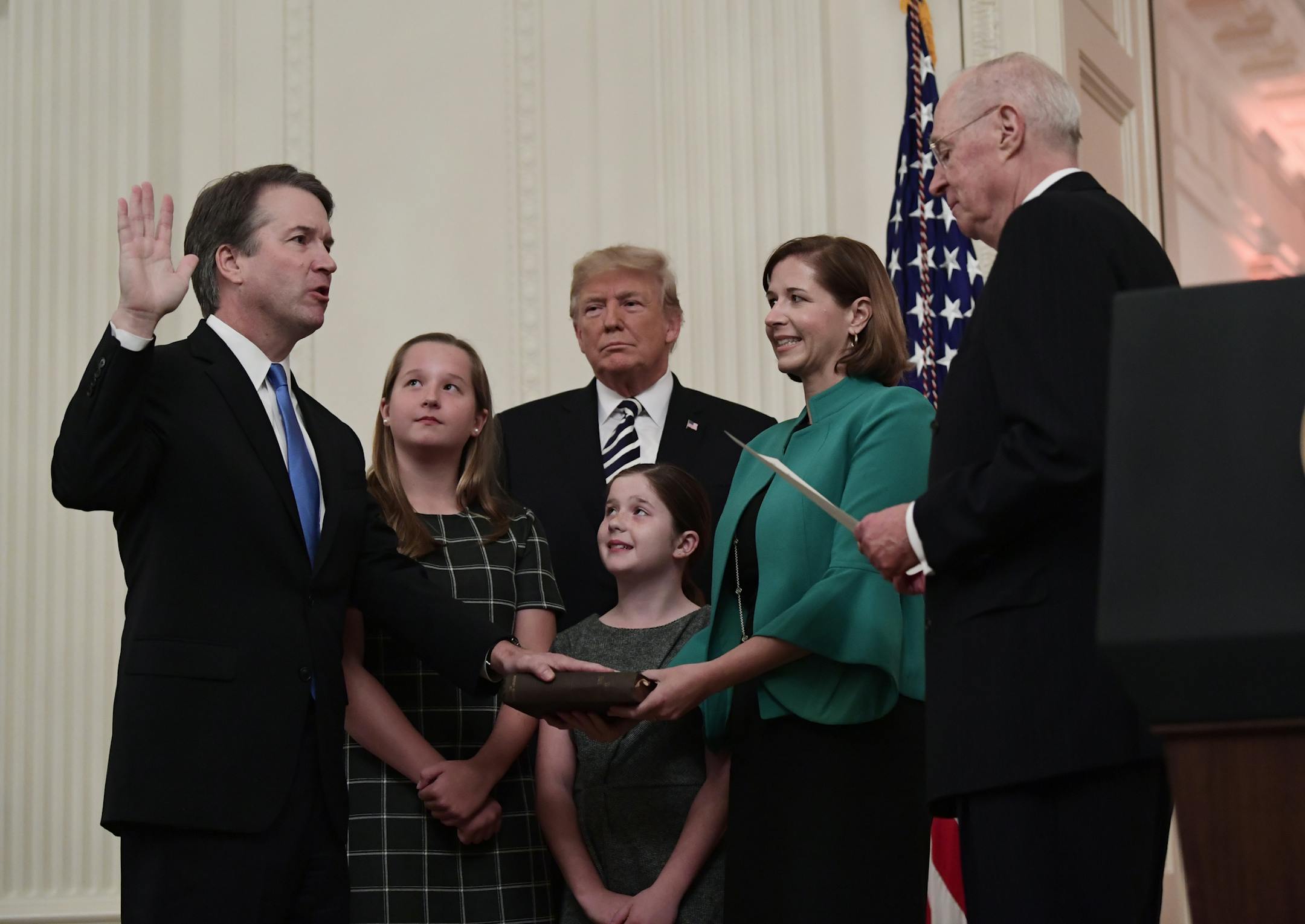 Retired Justice Anthony Kennedy, right, ceremonially swears-in Supreme Court Justice Brett Kavanaugh, as President Donald Trump looks on, in the East Room of the White House in Washington, Monday, Oct. 8, 2018. Ashley Kavanaugh holds the Bible and daughters Margaret, left, and Liza, look on. (AP Photo/Susan Walsh)