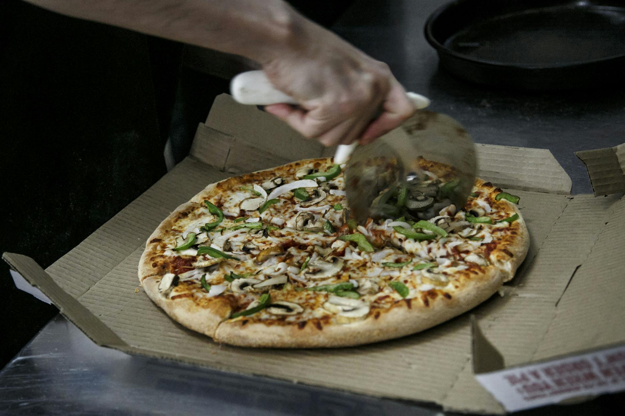 An employee cuts a pizza at a Domino's Pizza restaurant in Detroit on April 27, 2016. MUST CREDIT: Bloomberg photo by Sean Proctor.