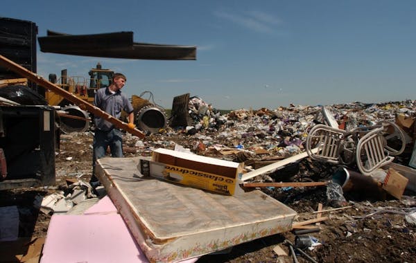 Joey McLeister/Star Tribune Burnsville,Mn.,Thurs.,July 8, 2004--Eric Olson, one of the Junk Squad employees, helps unload the last pieces of junk from