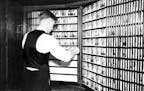 A worker looks through police booking photos in Hennepin County, ca. 1938