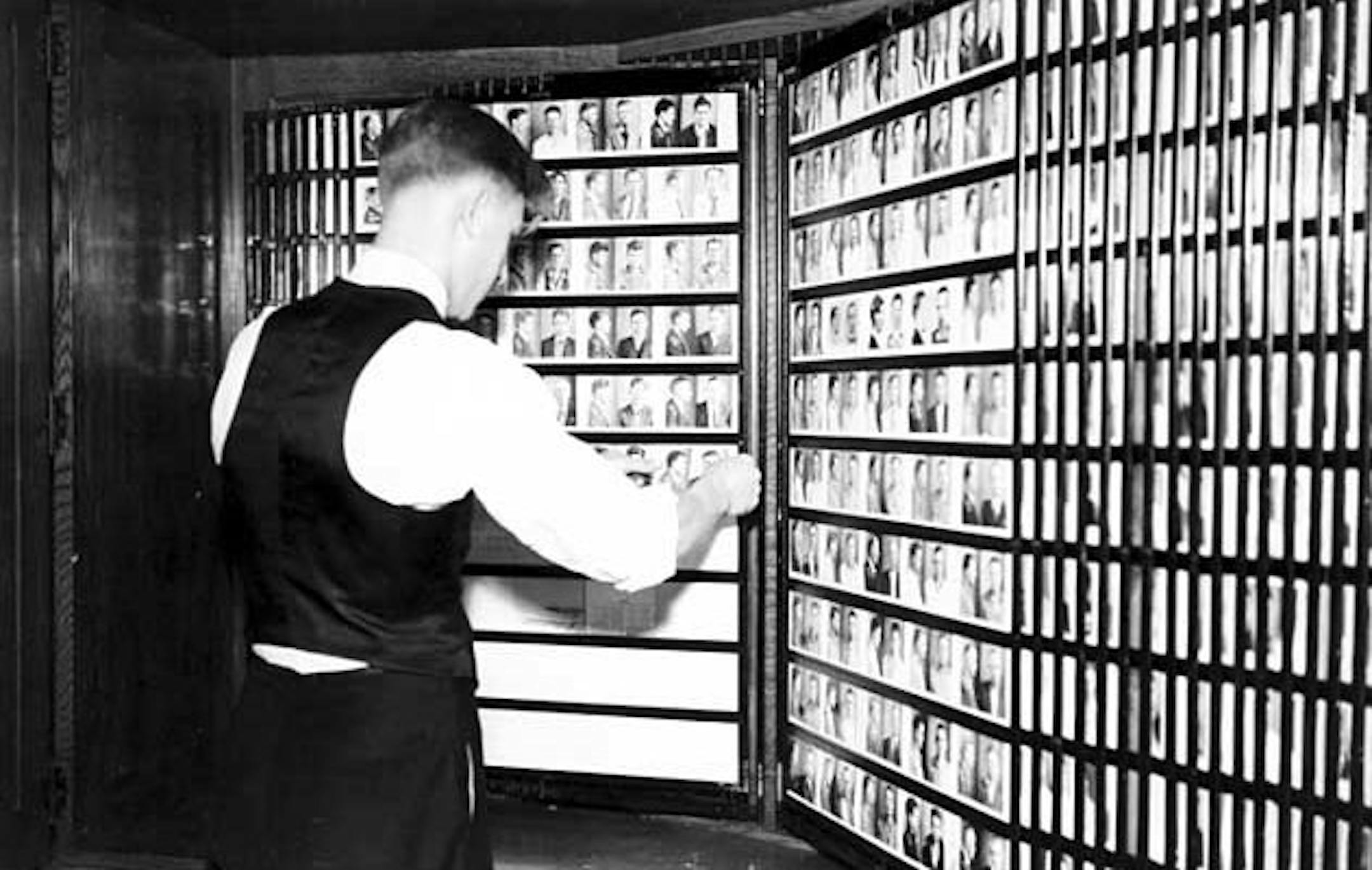 A worker looks through police booking photos in Hennepin County, ca. 1938