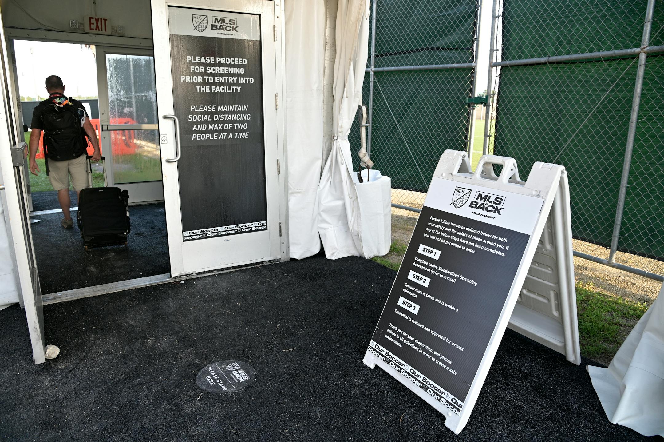 A member of the media walks through a health-screening checkpoint at a security entrance to the ESPN Wide World of Sports complex before an MLS soccer match between the Philadelphia Union and New York City FC, Thursday, July 9, 2020, in Kissimmee, Fla. (AP Photo/Phelan M. Ebenhack)
