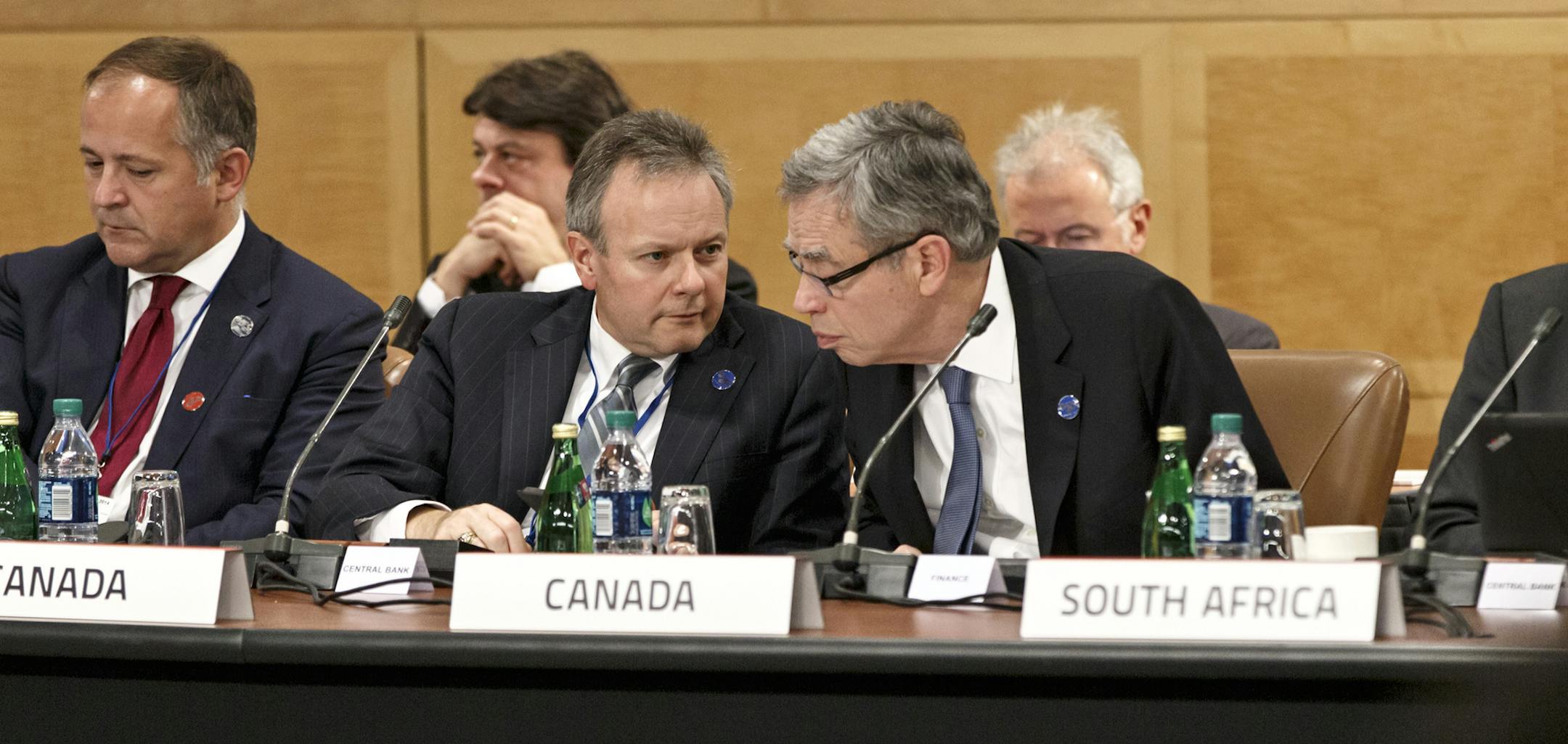 Canada's Minister of Finance Joe Oliver, center right, leans in to speak with Stephen Poloz, governor of the Bank of Canada, center left, as the Group of Twenty nations gather at the International Monetary Fund and World Bank meetings in Washington, Friday, Oct. 10, 2014. Finance officials from the world's largest economies are being urged to prevent the global economy from falling into a "new mediocre" in which growth remains stuck at sub-par levels for years to come, trapping millions of peopl