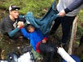 Addison Ditto is covered by his classmates who were trying to keep him warm after a falling tree broke his leg in North Idaho. (Courtesy photo/The Spo