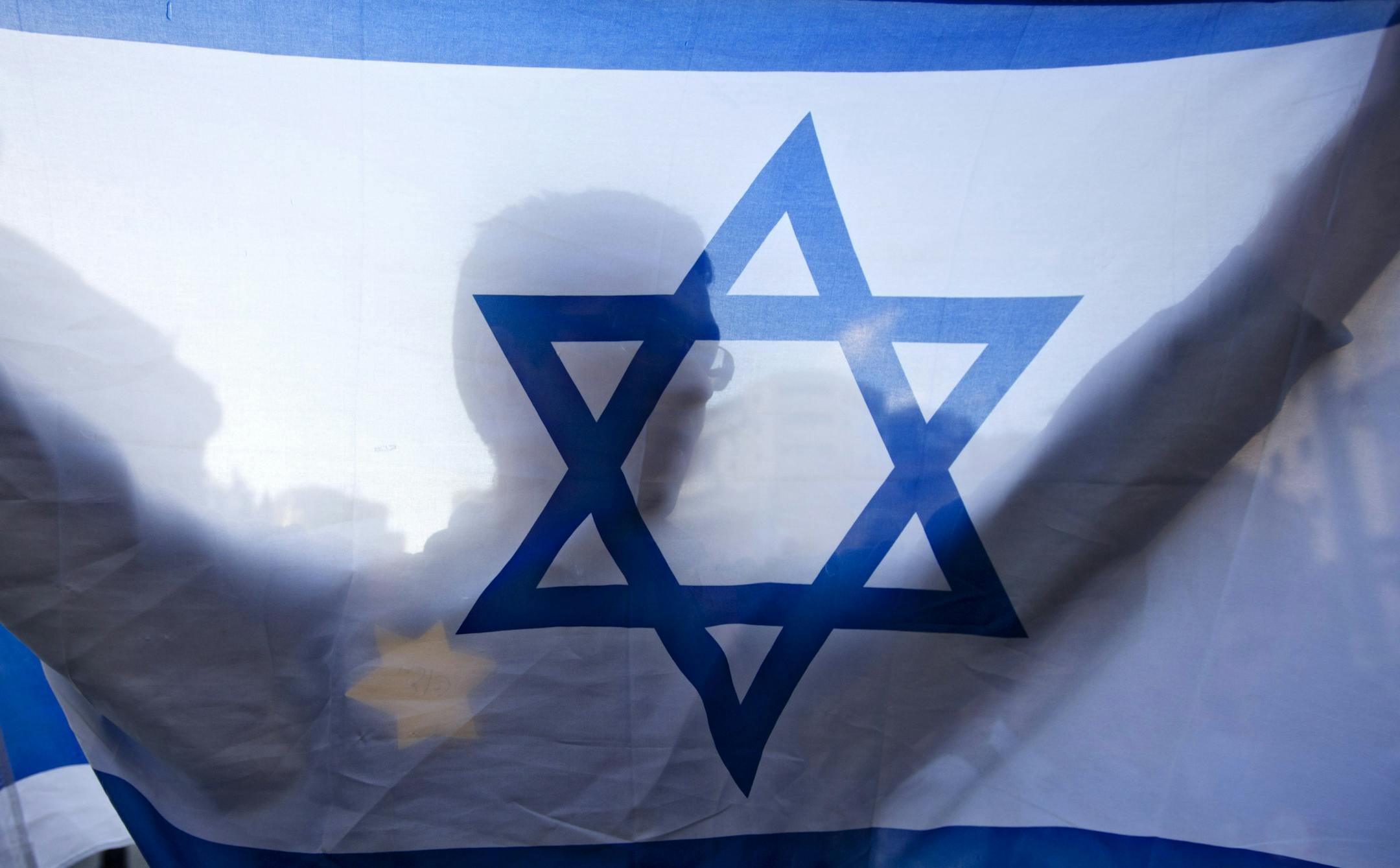 A right-wing Israeli holds a flag and wears a Star of David patch resembling the one Jews were forced to wear in Nazi Germany during a demonstration in Jerusalem, Monday, July 14, 2014. The demonstrators chanted "Israel for the Jews" in support of the Israeli military action in the Gaza Strip. Israel began its campaign against militants in the Hamas-controlled Gaza last Tuesday, saying it was responding to heavy rocket fire from the densely populated territory. (AP Photo/Sebastian Scheiner)