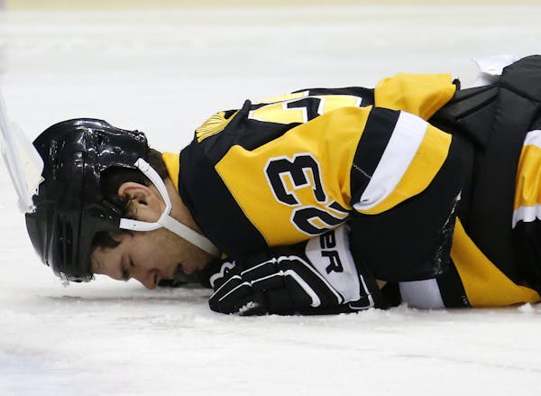In this Jan. 13, 2015 file photo Pittsburgh Penguins' Steve Downie (23) lies on the ice after taking an elbow to the face from Minnesota Wild defensem
