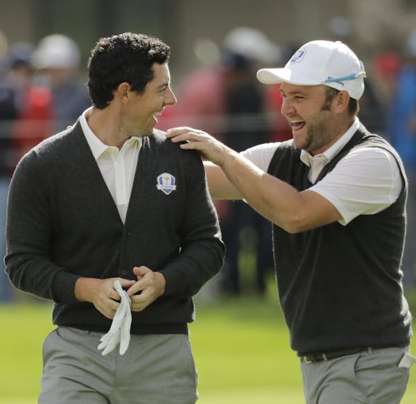 Europe's Andy Sullivan congratulates Europe's Rory McIlroy after McIlroy holed his approach shot on the sixth hole during a practice round for the Ryd