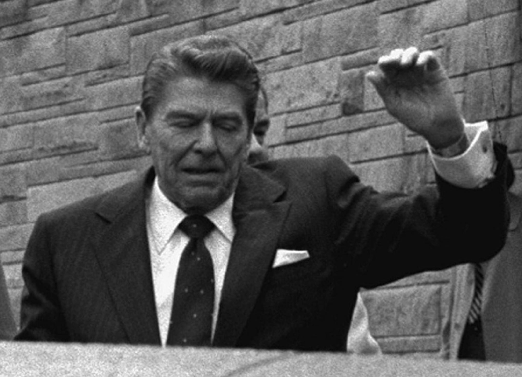 FILE - In this March 30, 1981, file photo, President Ronald Reagan winces and raises his left arm as he was shot by an assailant as he left a Washington hotel after making a speech to a labor group. The President was shot in the upper left side. A president’s first 100 days can be a tire-squealing roar from the starting line, a triumph of style over substance, a taste of what’s to come or an ambitious plan of action that gets rudely interrupted by world events.(AP Photo/Ron Edmonds