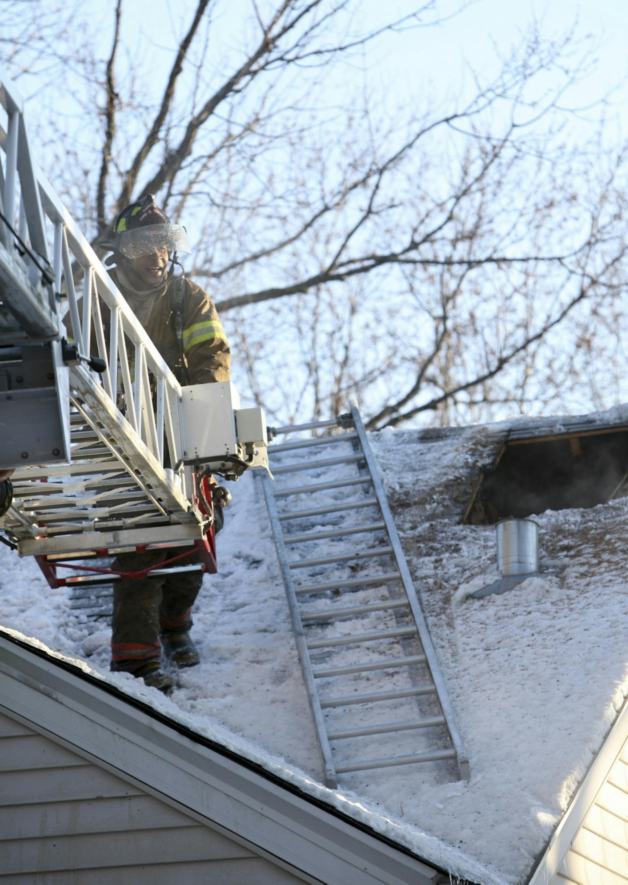 A St. Paul firefighter prepares to climb off the roof following a house fire at 1456 St. Albans St. in St. Paul on Monday, Jan. 2, 2012. A firefighter was burned after falling through the floor and into the basement while battling the fire.