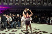 Tyler Kim holds up the "Swens-Milboy Belt," awarded to the winner of the Augsburg-Wartburg men's wrestling dual meet, after his win at 285 pounds clin