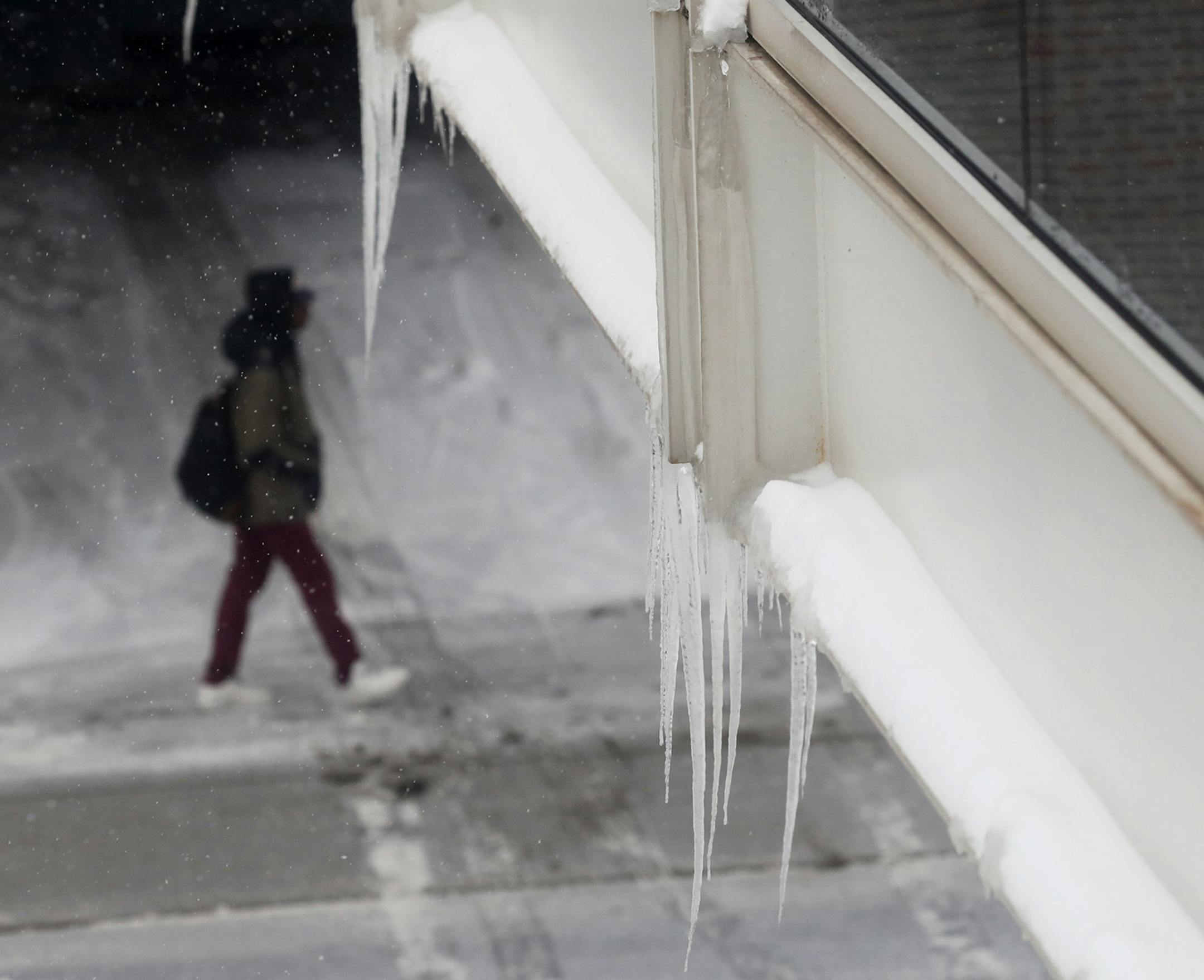 A pedestrian walks below icicles cling to a skyway along Third Ave. S in Minneapolis.