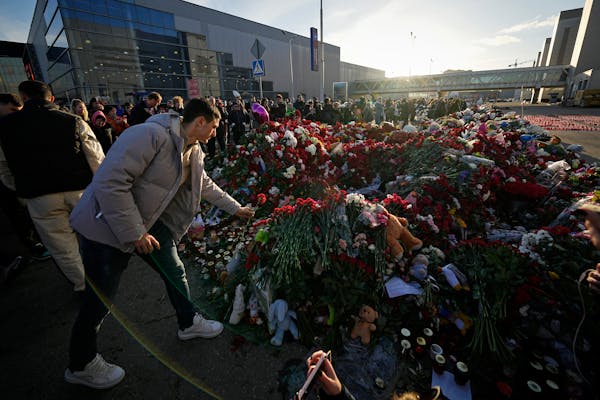 People place flowers at a makeshift memorial in front of the Crocus City Hall on the western outskirts of Moscow on Monday in the wake of terror attac