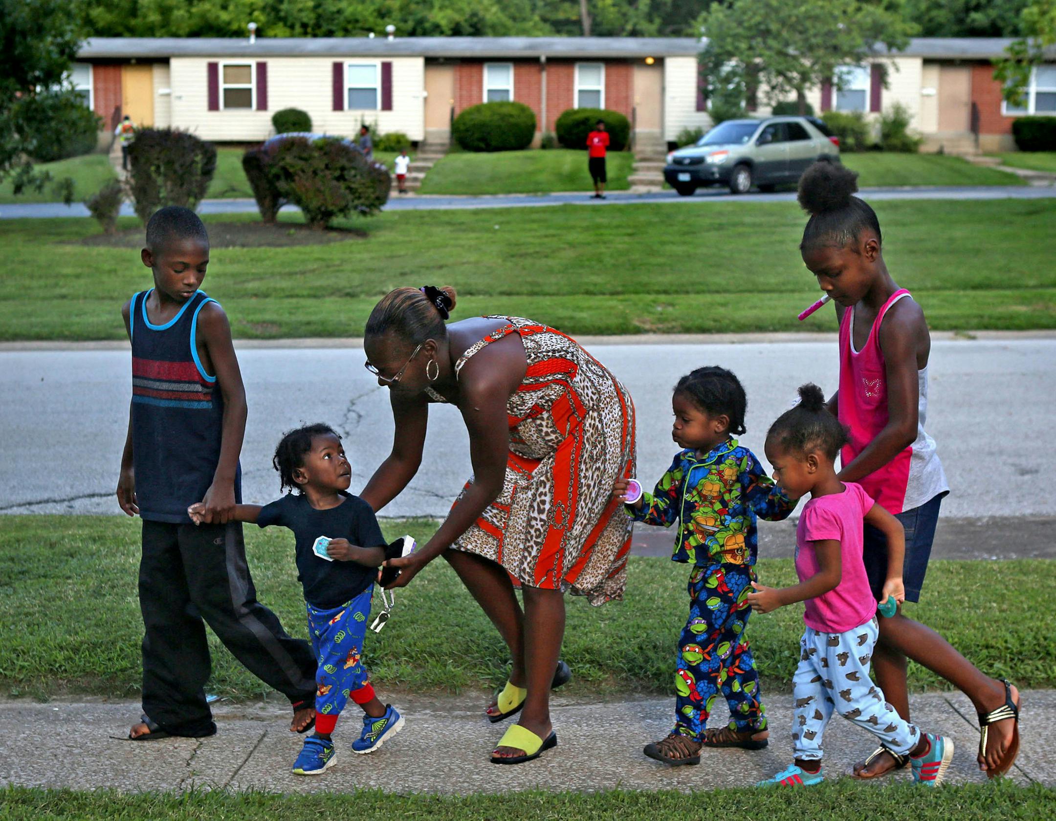 "I don't let them go outside anymore," said Darlene Evans as she takes a walk with her five youngest children on Wednesday, Aug. 12, 2015, in front of their home in Northwinds apartment complex in Ferguson, Mo. From left are to right are Warren, 10, Alex, 2, Evans, Aaron, 3, Lexi, 2, and Destiny, 9. Since some of her children witnessed a shooting outside their apartment four days earlier during Destiny's birthday party, Evans has limited her children's outside playtime. (Laurie Skrivan/St. Louis