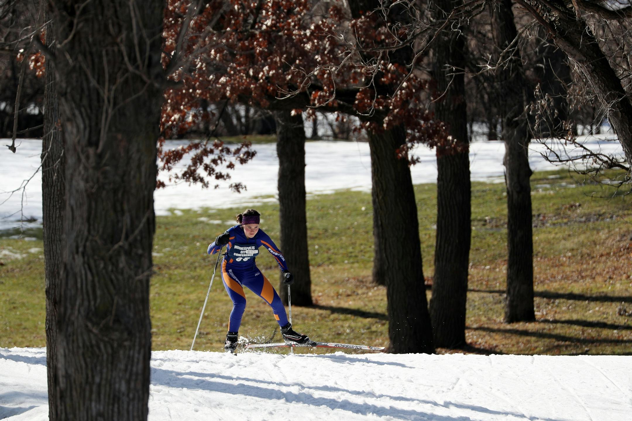 A young skier traversed the course at Thoedore Wirth Park as patches of grass from unseasonably warm weather can be seen.