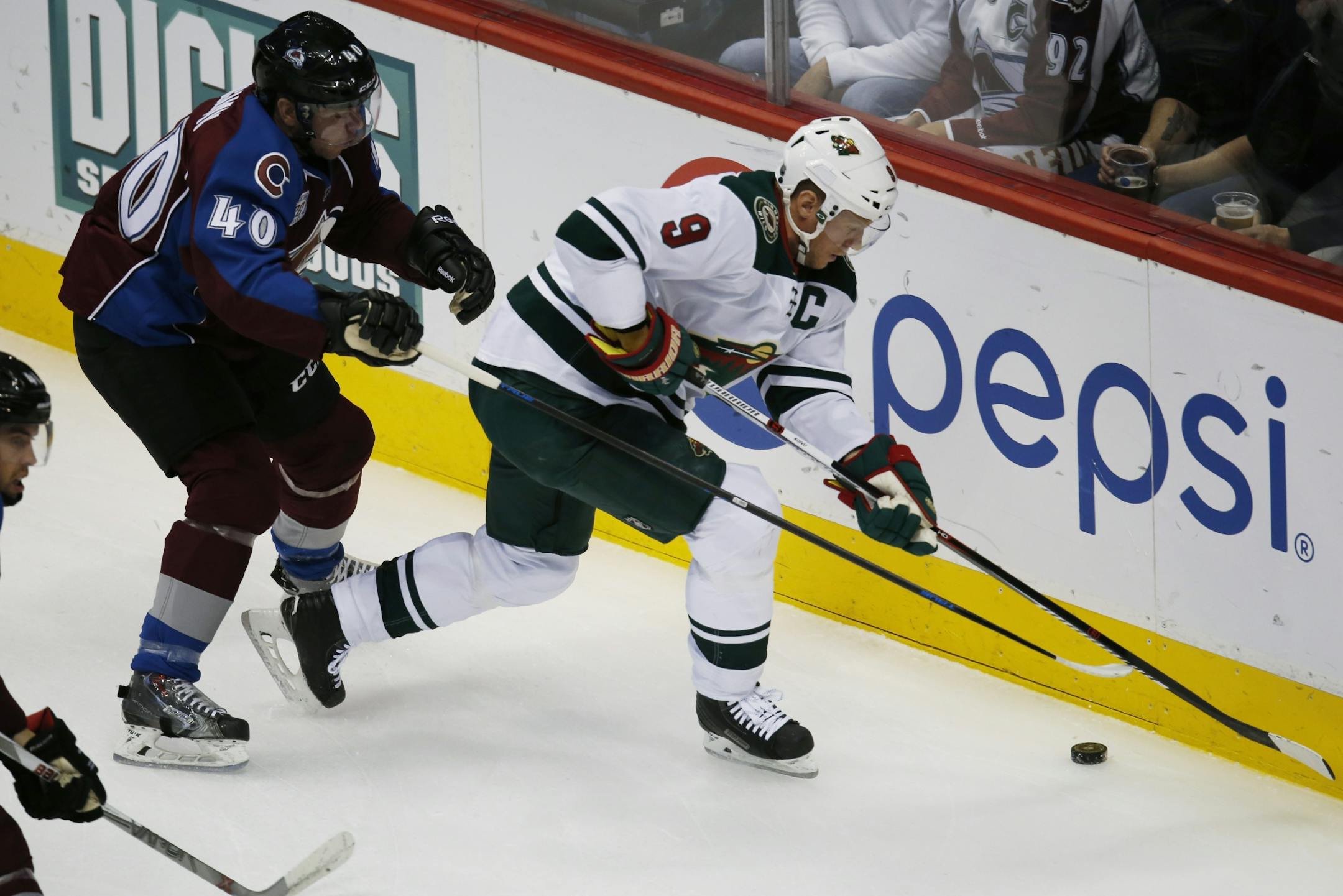 Colorado Avalanche left wing Alex Tanguay, left, battles for control of the puck with Minnesota Wild center Mikko Koivu,right, of Finland, in the first period of an NHL hockey game Monday, Dec. 7, 2015, in Denver.