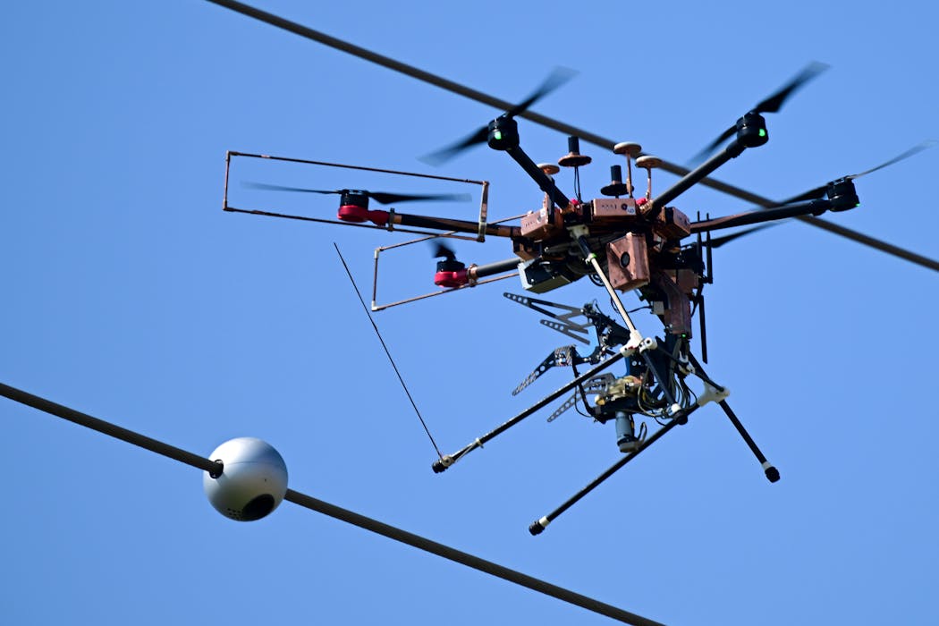 A drone flies backward before landing after installing a “Magic Orb” to a power line on April 30 in Maple Grove.