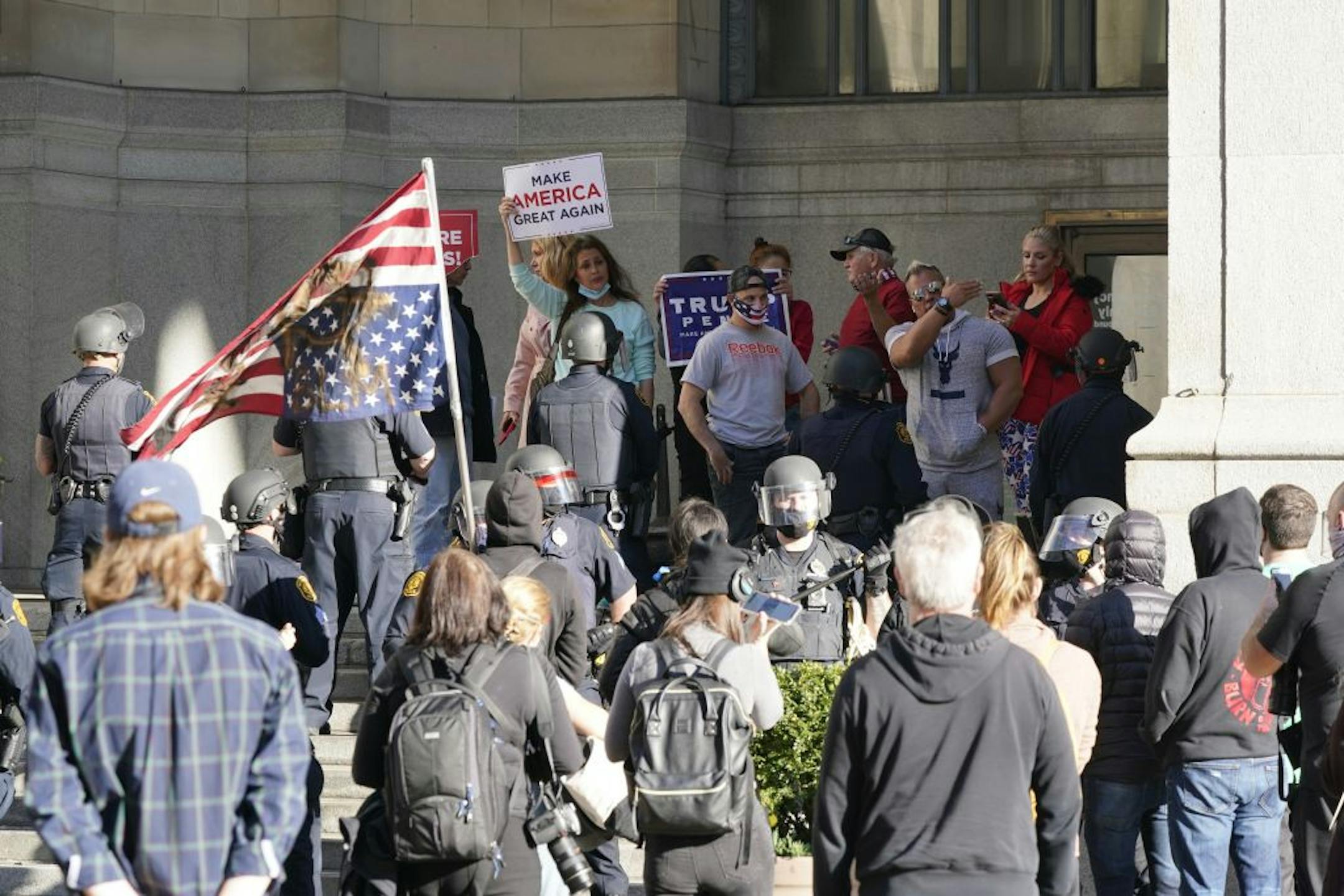 Pittsburgh police in riot gear line up in front of people at a "stop the steal" rally between them and an anti-Trump group outside The City County Building and a group that arrived later Friday, Nov. 6, 2020 in Pittsburgh.