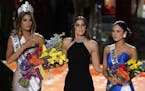 Former Miss Universe Paulina Vega, center, reacts before taking away the flowers, crown and sash from Miss Colombia Ariadna Gutierrez, left, before gi