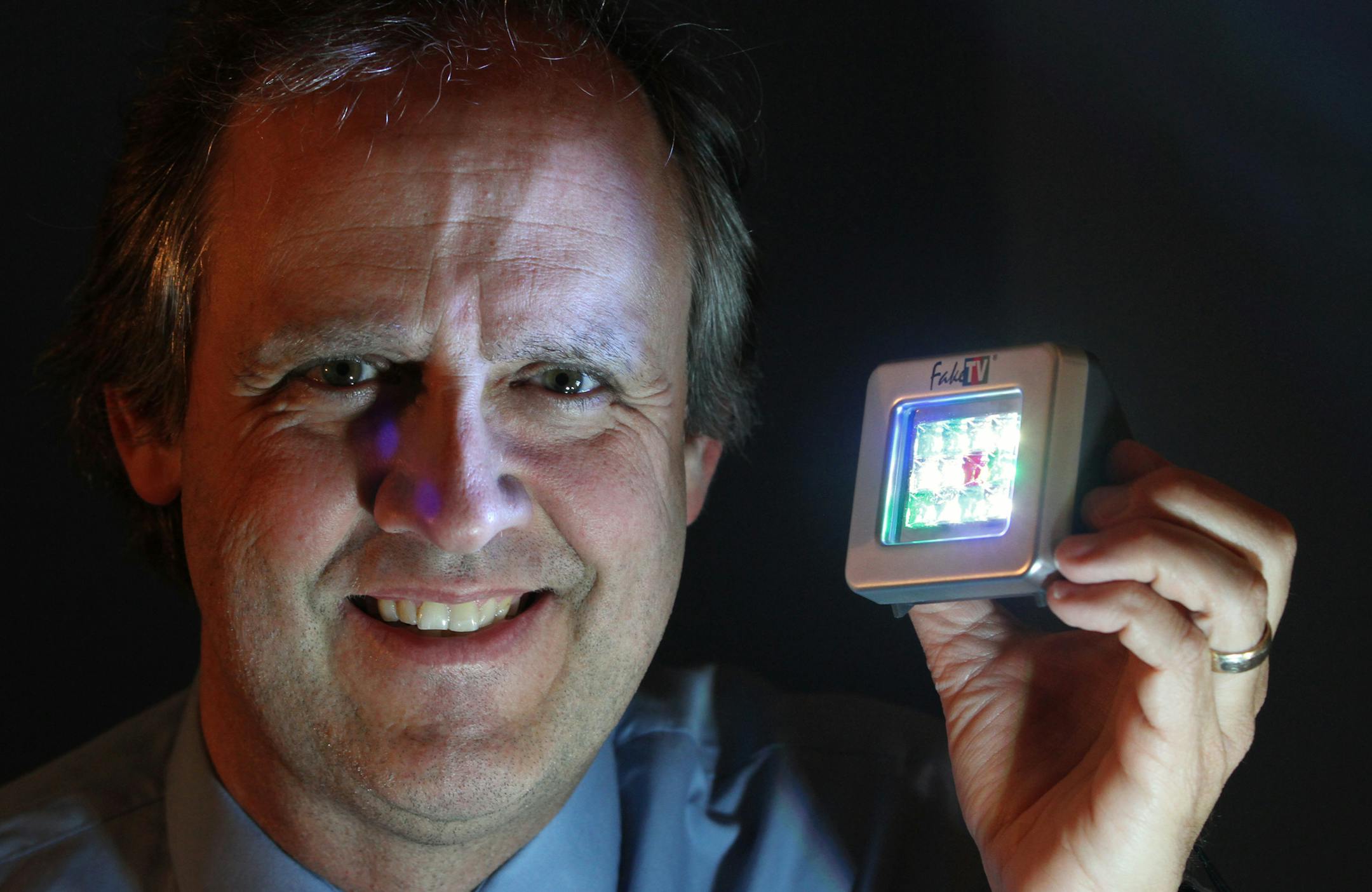 Rein Teder, the co-inventor of FakeTV, held one of his FakeTV units at his Eden Prairie office on 4/16/13. As spring fever has Minnesotans getting out of the house, burglars are lying in wait to get in. Rein Teder of Hydreon Corp in Eden Prairie has invented a device to keep them at bay, a FakeTV that mimicks the flickering of a TV when no one is home. It may not be as effective as a Brink's alarm, but burglars tend to choose the path of least resistance, say experts.] Bruce Bisping/Star Tribune