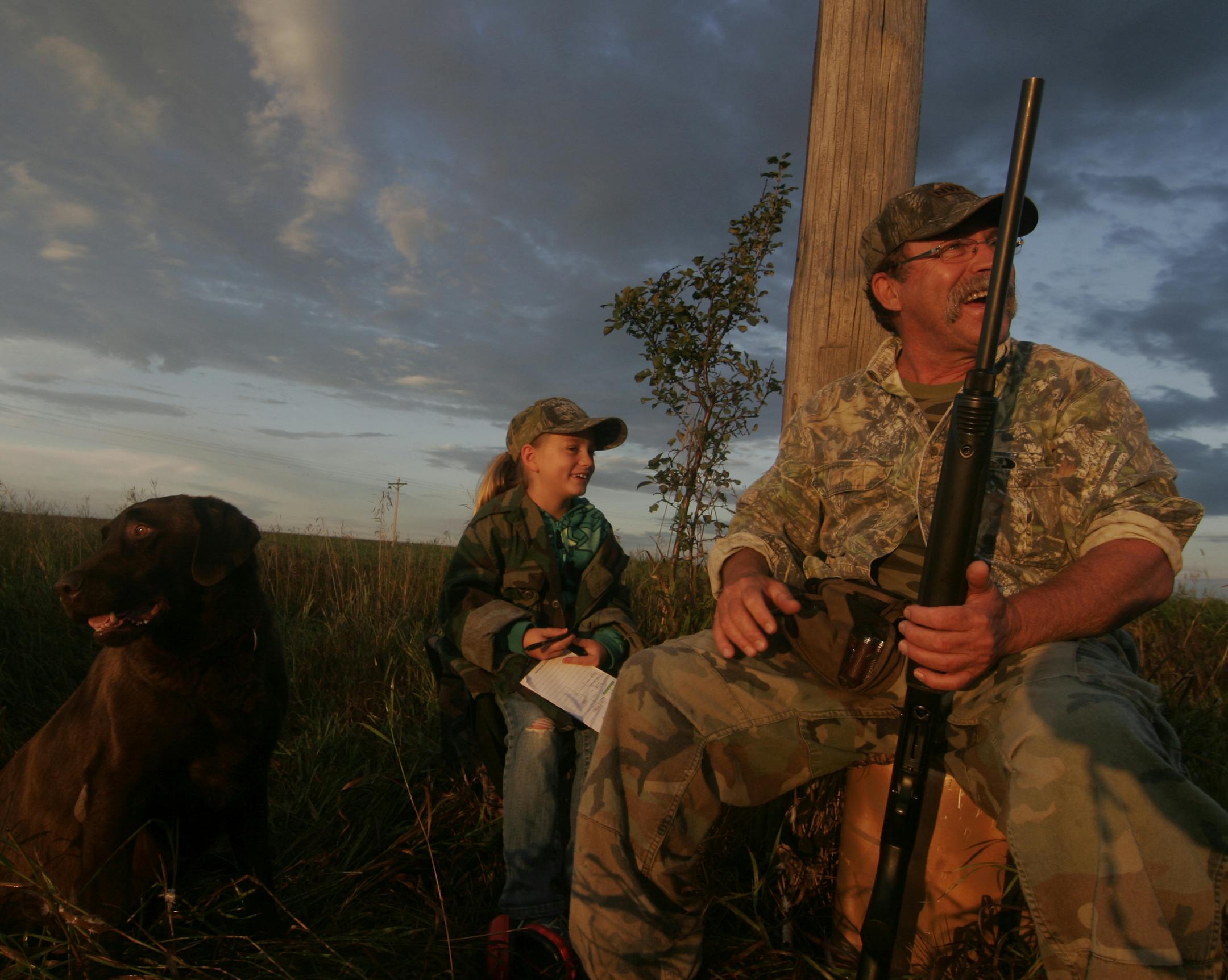 Tom Kalahar of Olivia, Minn., awaits mourning doves during the dove season opener on Monday. With him was granddaughter Emily Luebben, 7, of Alberville, who had a pad of paper to record his missed shots. "I going to need more ink,'' she said later after several misses. Waiting for some action is Jack, Kalahar's Lab.
