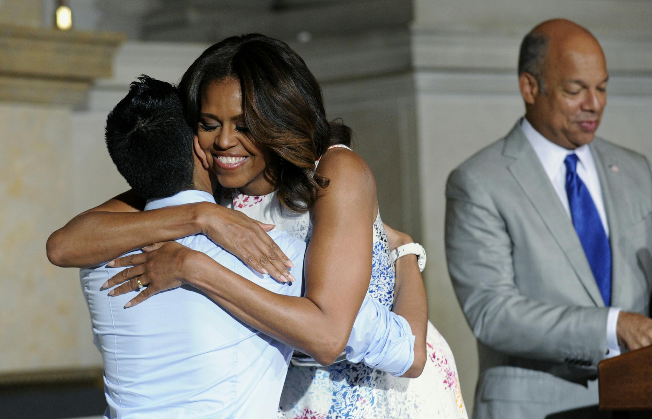 First lady Michelle Obama hugs Juan Cua Monroy, 20, originally from Guatemala, after he was sworn in as a U.S. citizen during a naturalization ceremony at the National Archives in Washington, Wednesday, June 18, 2014. Homeland Security Secretary Jeh Johnson is at right. (AP Photo/Susan Walsh)
