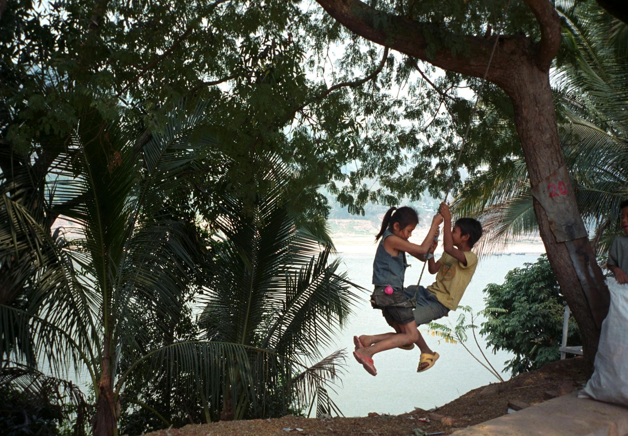 KRT TRAVEL STORY SLUGGED: WLT-LAOS KRT PHOTO BY THOMAS SWICK/SOUTH FLORIDA SUN-SENTINEL (MIAMI OUT) (October 31) Kids swing on the banks of the Nam Khan River in Luang Prabang, Laos. (gsb) 2004