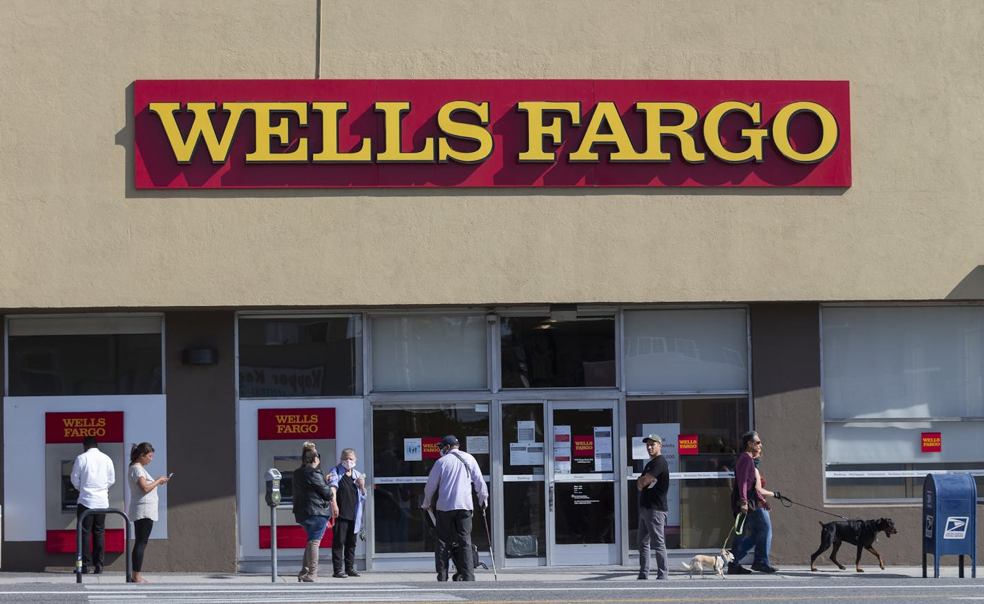 Customers, some wearing face masks, line up outside a Wells Fargo branch inf Los Angeles on Friday, April 3, 2020.