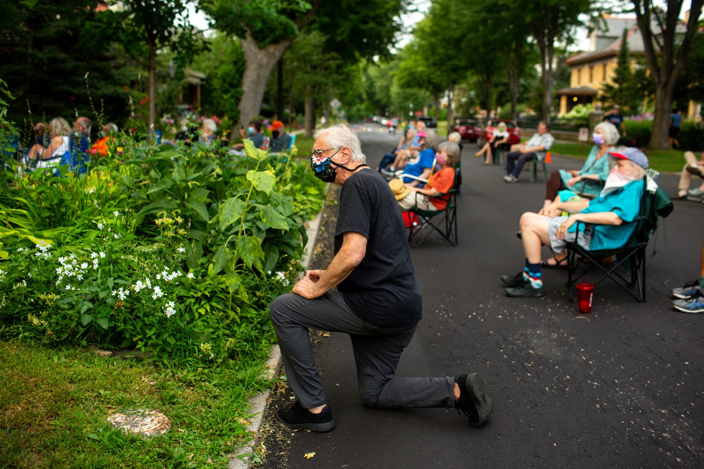 [A front yard performance by guitarist Pat Donohue of "Praire Home Companion" was hosted at Dick CohnÕs home in St. Paul Friday, August 7, 2020. NICOLE NERI ¥ Special to the Star Tribune] Dick Cohn kneels to take a video at a front yard performance by guitarist Pat Donohue of "Praire Home Companion" at his home in St. Paul Friday, August 7, 2020.