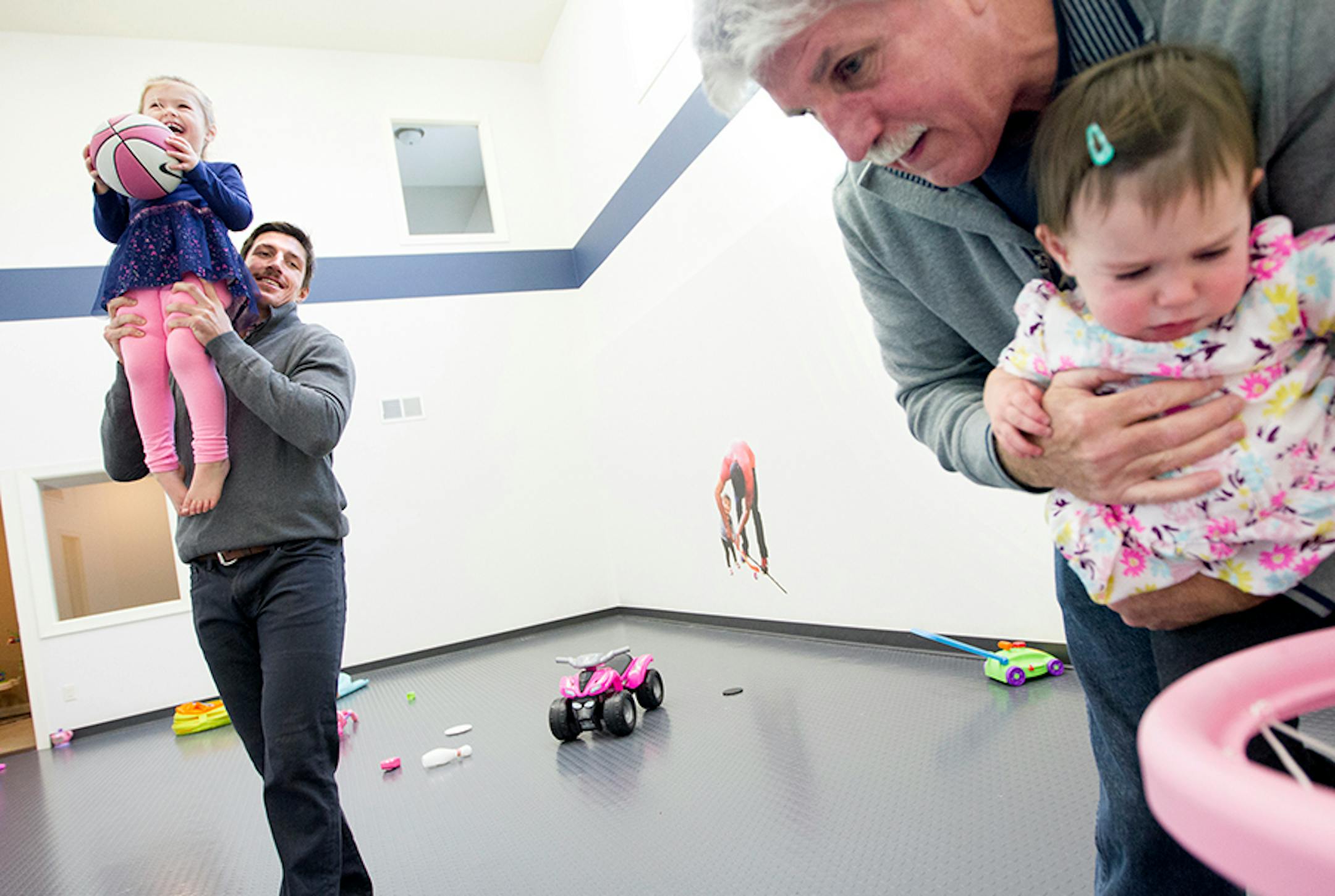 Minnesota Wild's Ryan Carter, left, holds his daughter Maggie, 3, up for a basket while his dad, Mike Carter, holds Ryan's younger daughter Natalie, 15 months, at Ryan's home in Gem Lake November 22, 2015.