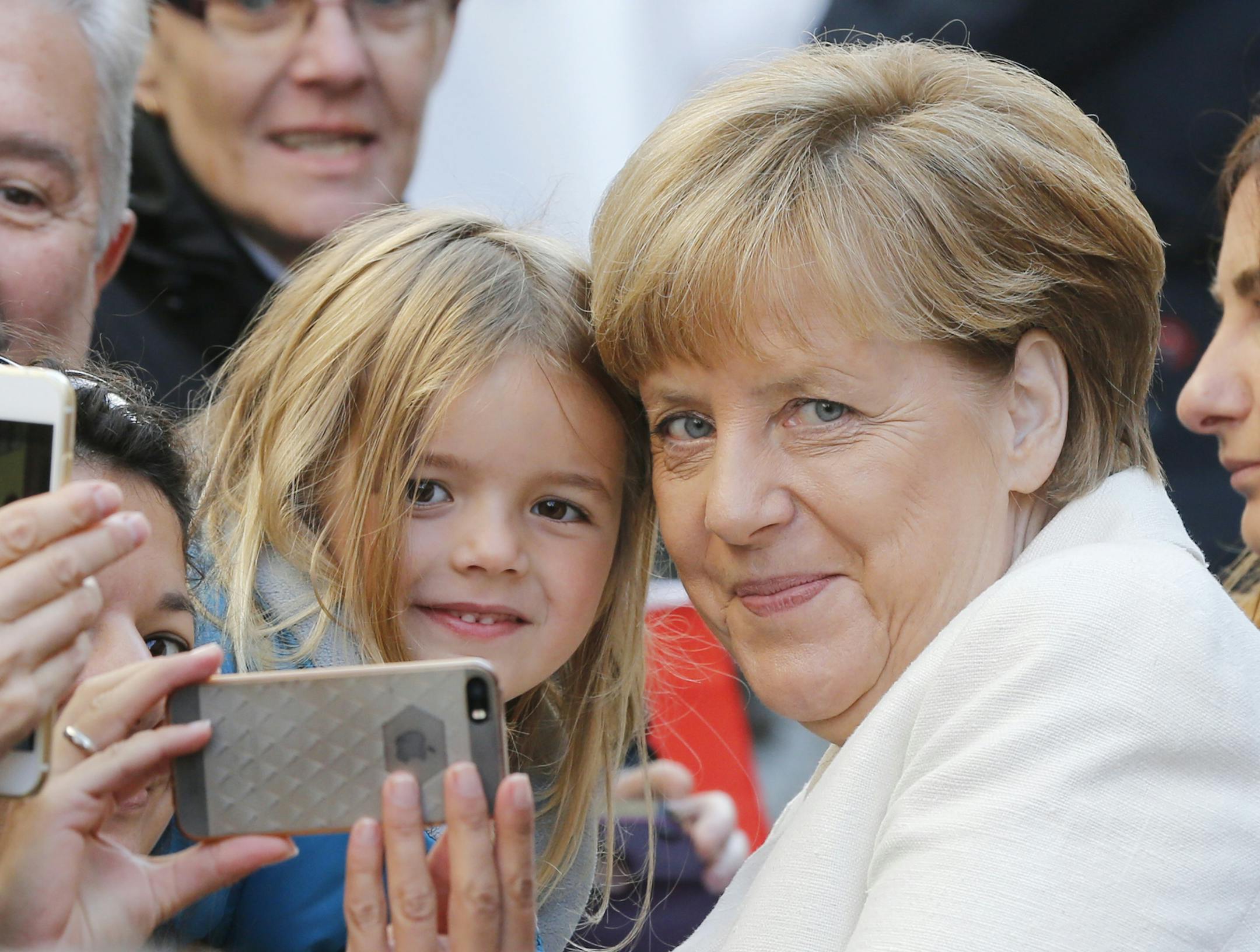 German Chancellor Angela Merkel poses for a selfie with 5-year-old Marie during the celebrations marking the 25th anniversary of the German Unification in Frankfurt, Germany, Saturday, Oct. 3, 2015. (AP Photo/Michael Probst)