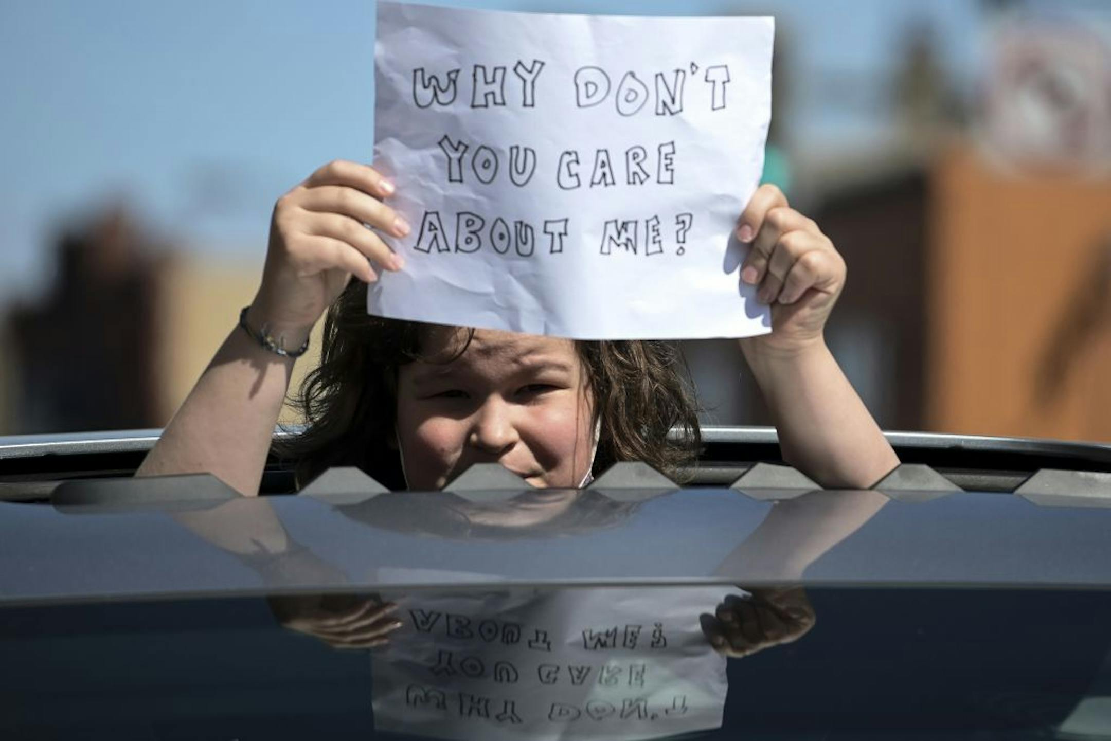 A child protester stood out the sun roof of a car during Friday's anti-CDD drive-by protest in front of the Minneapolis Public School headquarters in north Minneapolis Friday.