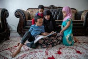 Fardowsa Bashir sat with her children, Saadiq Dahir, 6, left, Sadri, 2, center, and Anzal, 3, right, as she listened to them read to her in her home i