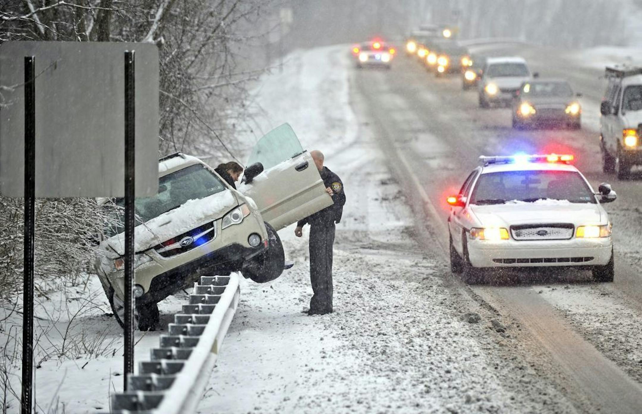 A Patton Township police officer helps a woman out of her vehicle after she slid off N. Atherton Street and was stranded on top of a guard rail, Monday, Feb. 3, 2014, A winter storm in Centre County Monday, February 3, 2014, caused heavy snowfall and dangerous travel conditions. The winter storm hitting Pennsylvania has prompted school closures, lower speed limits and hours-long airport delays. (AP Photo/Centre Daily Times,Nabil K. Mark) MAGS OUT Mandatory Credit