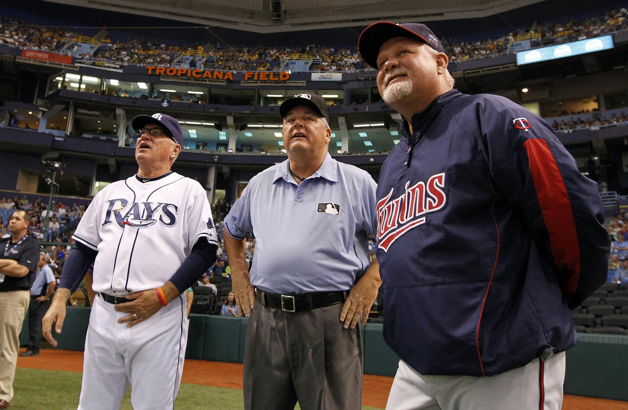 Tampa Bay Rays manager Joe Maddon, left, and Minnesota Twins manager Ron Gardenhire, right, speak with umpire crew chief Jerry Crawford about the power outage that delayed the start of a baseball game, Wednesday, Aug. 4, 2010, in St. Petersburg, Fla.