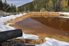 In this Oct. 12, 2018 photo, water contaminated with arsenic, lead and zinc flows from a pipe out of the Lee Mountain mine and into a holding pond nea