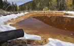 In this Oct. 12, 2018 photo, water contaminated with arsenic, lead and zinc flows from a pipe out of the Lee Mountain mine and into a holding pond nea