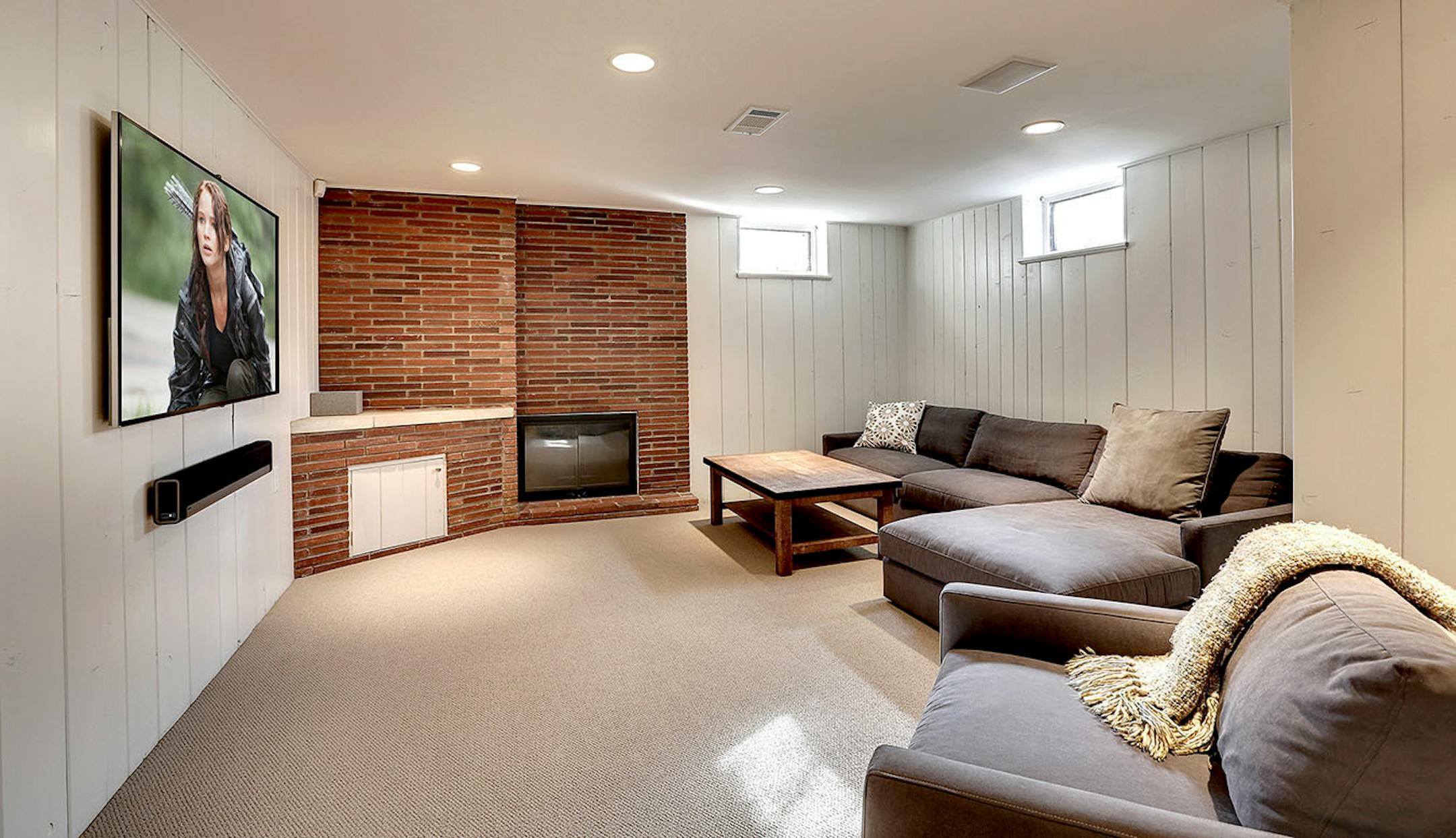 The basement was updated and refreshed with white paint covering the dark knotty pine paneling and new carpet.