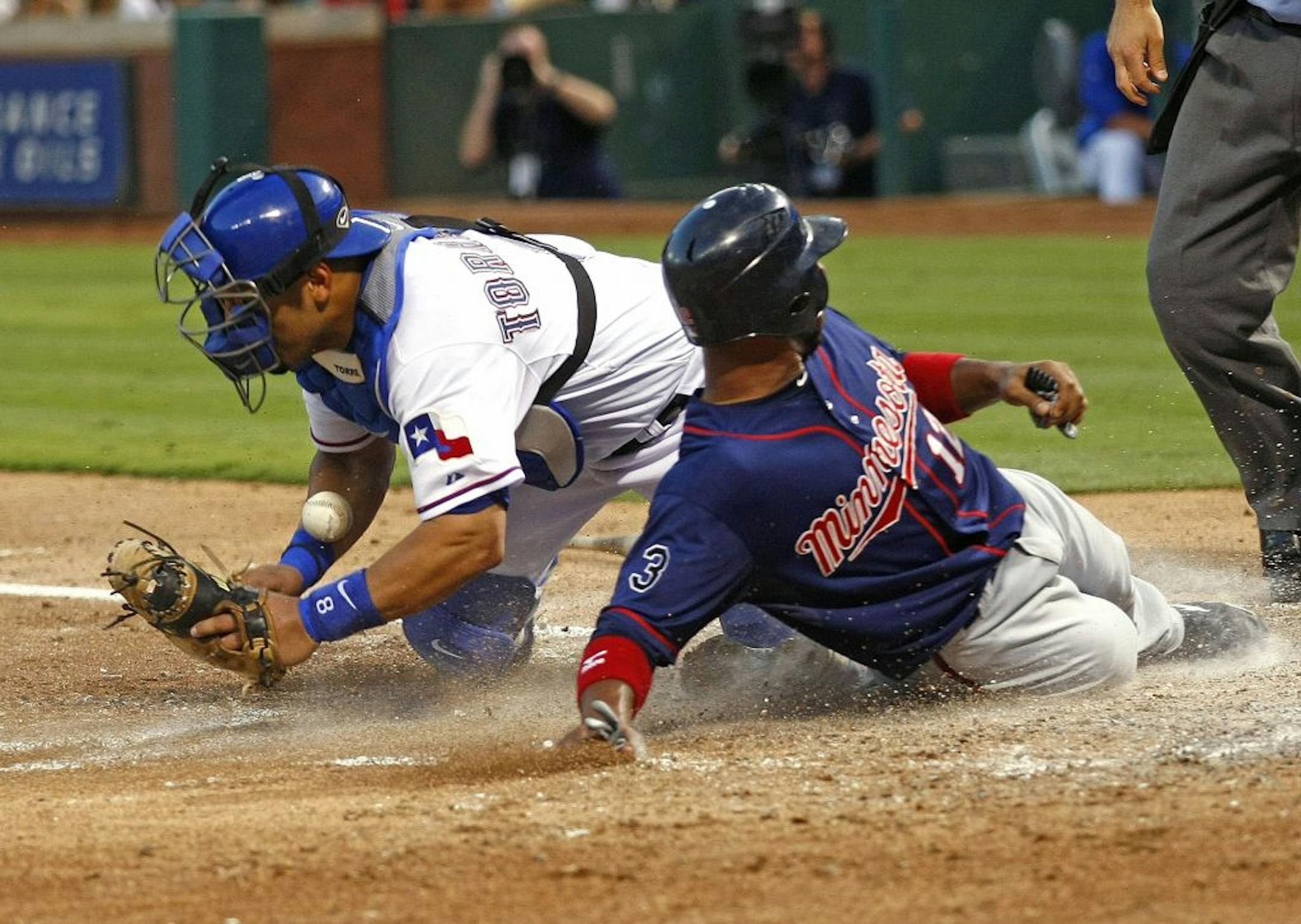 Minnesota Twins second baseman Alexi Casilla slides safely past Texas Rangers catcher Yorvit Torrealba during the 4th inning in Arlington, Texas Wednesday, July 27, 2011.