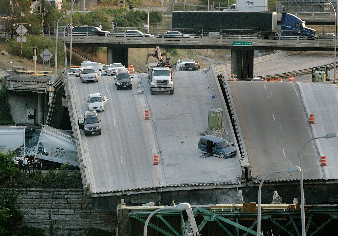 Rescue personnel (left) look over the scene of the I-35W bridge collapse at first light Thursday.