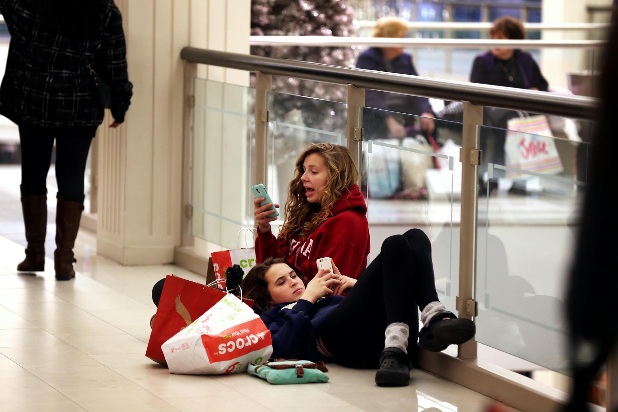 Maija Tanberg, 15, in red, and Grace VanBergen, 15, both of Forest Lake, rest while shopping in the late morning on Black Friday at Mall of America in Bloomington on Friday, November 28, 2014. They had been shopping since 4 a.m.